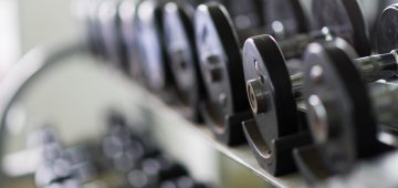 Rows of metal dumbbells on rack in the gym / sport club. Weight Training Equipment.